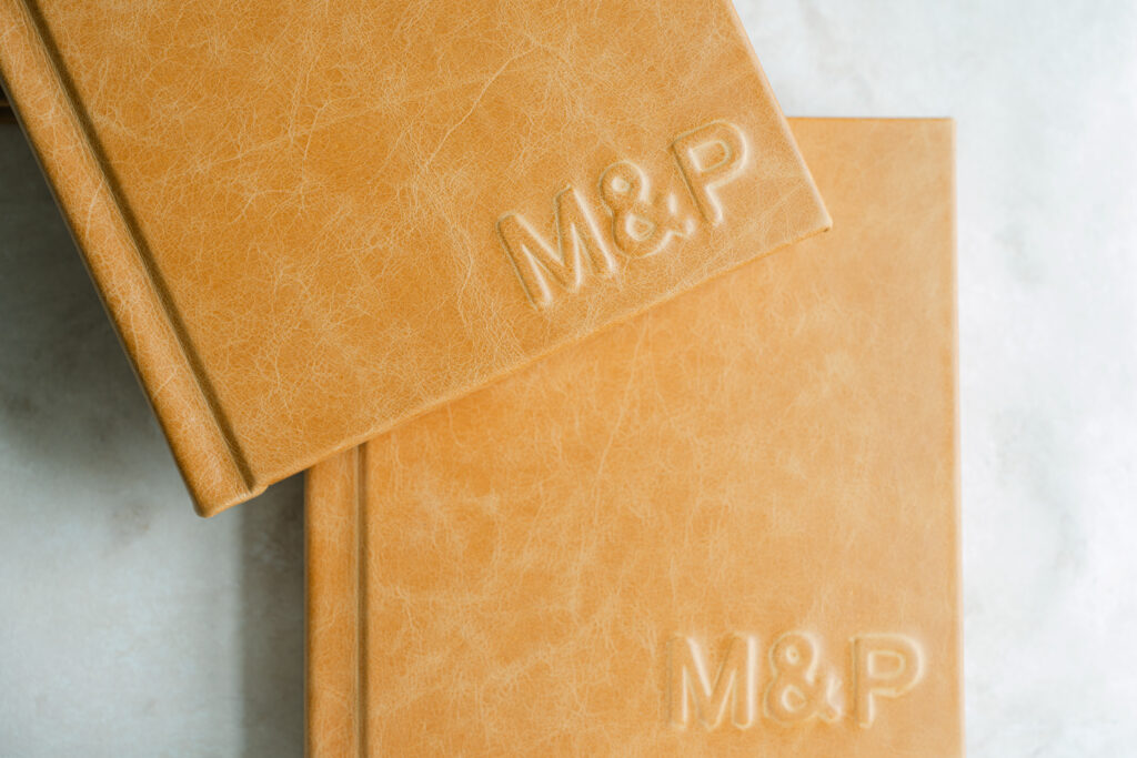 Heirloom wedding albums on display, whiskey colored leather with raised initials. 
